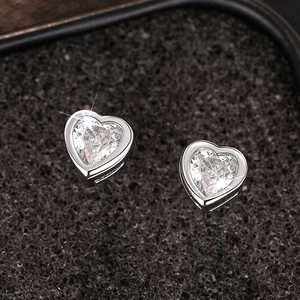 Macro shot of silver heart studs with sparkling stones on black sponge texture