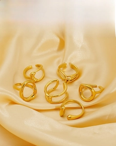Detail of diverse geometric stainless steel rings with 18k gold plating on yellow silk