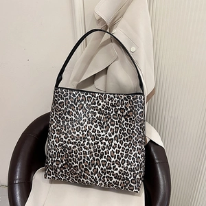 Chic leopard print oversized shoulder tote bag with black straps on a leather chair