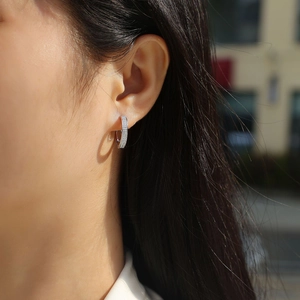 Close-up of silver hoop earrings featuring double rows of moissanite on a model