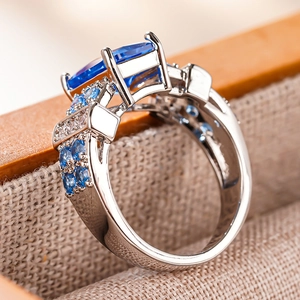 Macro shot of rectangular blue gemstone ring with intricate diamond-encrusted silver band