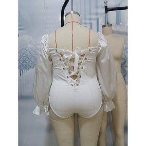 Détail d'un body en satin blanc avec laçage au dos et poignets à volants