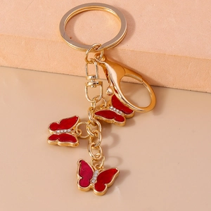 Detail of golden keychain with three red enamel butterflies and sparkling crystal accents
