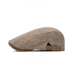 Detail view of brown herringbone newsboy hat featuring adjustable side leather strap