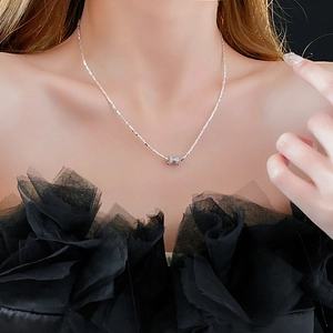 Détail du collier avec pendentif nœud argenté et pierres scintillantes sur un mannequin