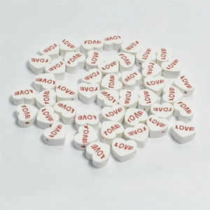 Macro shot of 10mm white heart-shaped polymer clay beads with red LOVE lettering detail