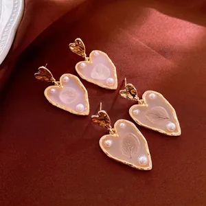 Gold plated heart drop earrings with dried leaves and white pearls on brown satin