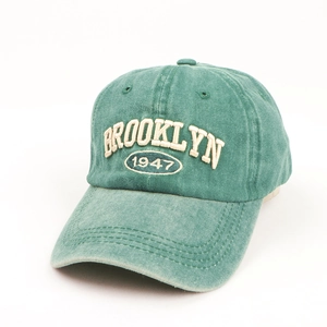 Detail of white Brooklyn 1947 embroidery on washed green vintage denim baseball cap