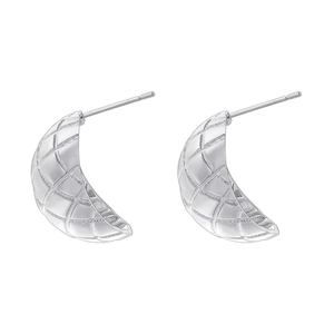 Detail showing C-shaped silver metal earrings with a geometric quilted texture design