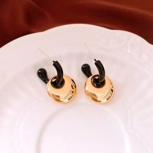 Macro detail of geometric drop earrings with gold plates on a ceramic tray