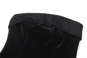 Detalle del escote fruncido y la textura de terciopelo de un vestido negro ajustado