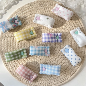 Cute fabric cable organizers in pastel colors and heart buttons on woven mat background