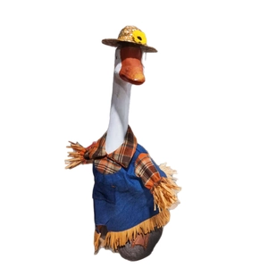 Garden goose statue in a denim dress, plaid shirt, and straw hat on a white background