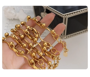 Detailed view of layered gold-plated chunky link chain bracelets with spherical charms