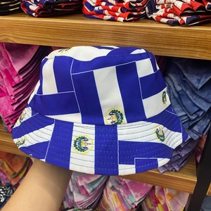 Detail of hand-held reversible bucket hat featuring El Salvador flag emblems on stripes