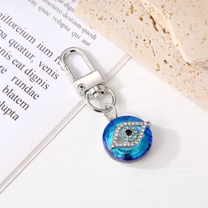 Elegant blue crystal evil eye keychain with silver ring on a minimalist background