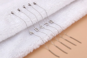 Detail view of silver titanium bracelets with A to E rhinestone letters on plush fabric