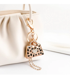Detail of leopard print handbag keychain with rhinestone heart on white pleated bag