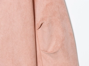 Detail of pink faux suede jacket showing textured fabric and precision pocket stitching