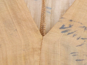 Close-up of V-neck stitching on khaki printed crinkle fabric with irregular blue patterns
