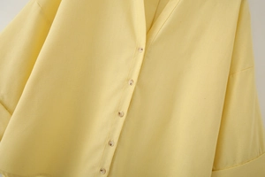 Detailed macro view of the yellow linen blend shirt showing V-neck and button closures
