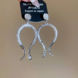 Macro shot of silver snake-shaped earrings with sparkling cubic zirconia on 925 silver