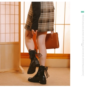 Detail of black calf socks with large organza bow paired with platform leather shoes