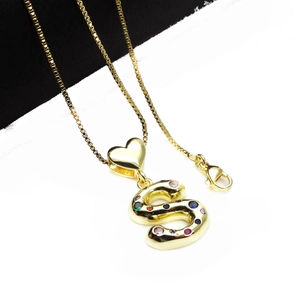 Detailed macro view of gold-plated letter S pendant with colorful cubic zirconia stones