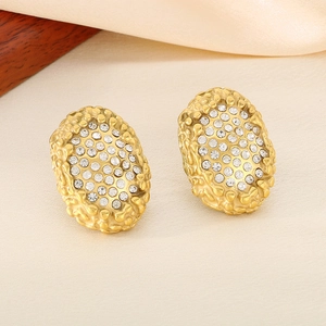 Detail of oval gold earrings featuring honeycomb texture and shimmering white rhinestones