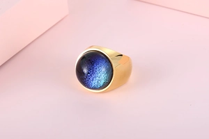 Detailed close-up of a wide gold ring with a sparkling blue gradient glass stone
