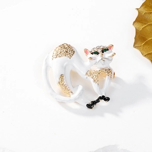 Detail of a gold cat brooch with white enamel, crystal rhinestones, and green eyes