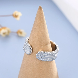Detail of silver stainless steel ring with wave texture on a wooden stand