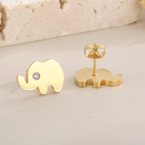 Macro view of gold elephant stud earrings featuring white zircon eyes on stone texture