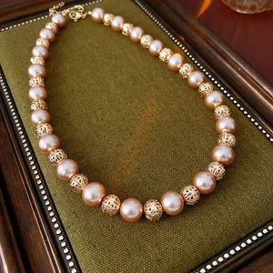 Detail of pink pearl beads and hollow golden metal beads on a vintage velvet tray