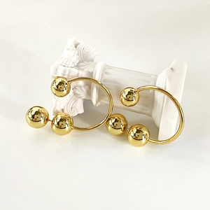 Minimalist golden spherical earrings with mirror finish on white classical pedestal