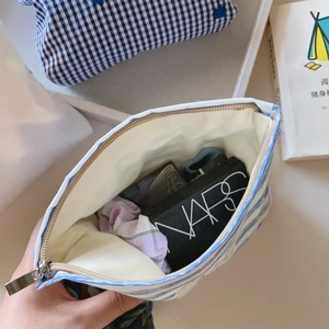 Detail view of large capacity blue white striped cosmetic bag with zipper and white lining