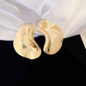 Detailed macro view of glossy irregular gold wave earrings with a liquid metal texture