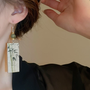 Detail of Chinese style earring with green bead and ink bamboo pattern on pendant