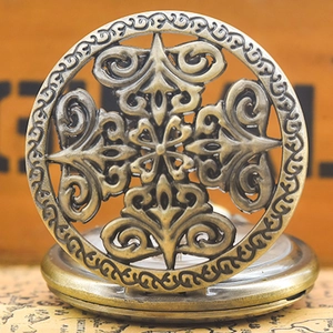 Close-up of vintage bronze quartz pocket watch with floral hollow-out lid on a wooden desk