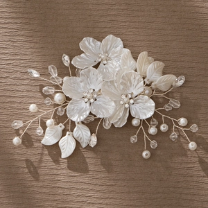 Detailed bridal hair clip featuring white handmade flowers, crystals, and pearls