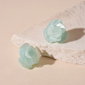 Detailed view of light green resin rose earrings with a pearlescent shimmer finish