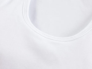 Close-up of white ribbed knit fabric detailing neckline stitching and soft texture