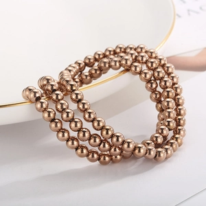 Close-up of rose gold elastic bead bracelets on elegant white porcelain plate