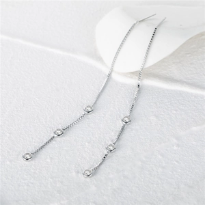 Macro detail of long S925 silver box chain tassel earrings with triple clear zircon stones