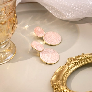 Elegant pink marble texture round earrings with golden edges on a neutral background