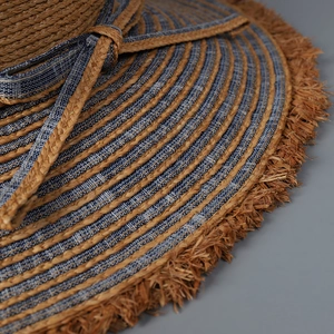 Macro shot of denim and raffia straw stitching with frayed edges on a sun hat
