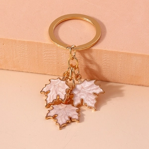 Close-up of golden keychain featuring three pink and white maple leaf enamel charms