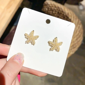 Close-up of starfish stud earrings featuring petite pearls and elegant gold finish