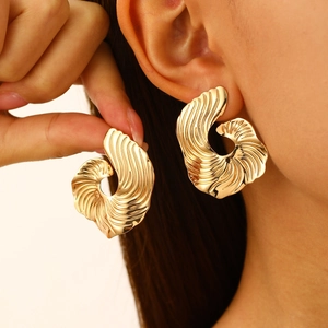 Detailed close-up of textured gold fan-shaped earrings with irregular metallic ripples