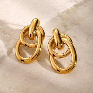 Detail of interlocking gold stainless steel earrings on a textured stone surface